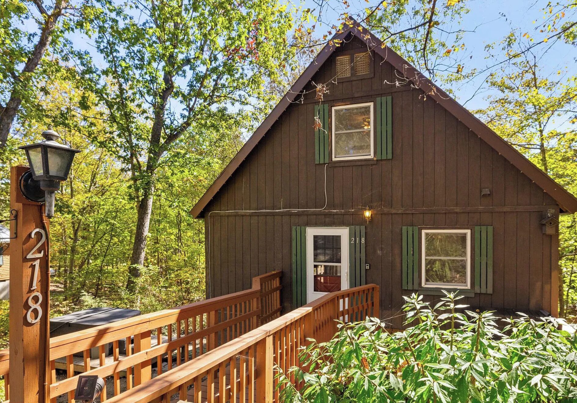 Une cabane rustique dotée d’une terrasse en bois et d’un petit porche.