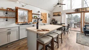 A spacious kitchen with a large island, wooden accents, and a view to the outdoors. - Cece's Chalet: Hot Tub * New Owner Offer (Mount Jackson)