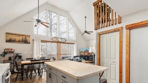 A spacious kitchen with a large island, wooden beams, and a dining area with a high ceiling and large windows. - Cece's Chalet: Hot Tub * New Owner Offer (Mount Jackson)