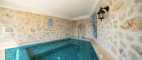 A stone-walled room with a hexagonal tiled pool.
