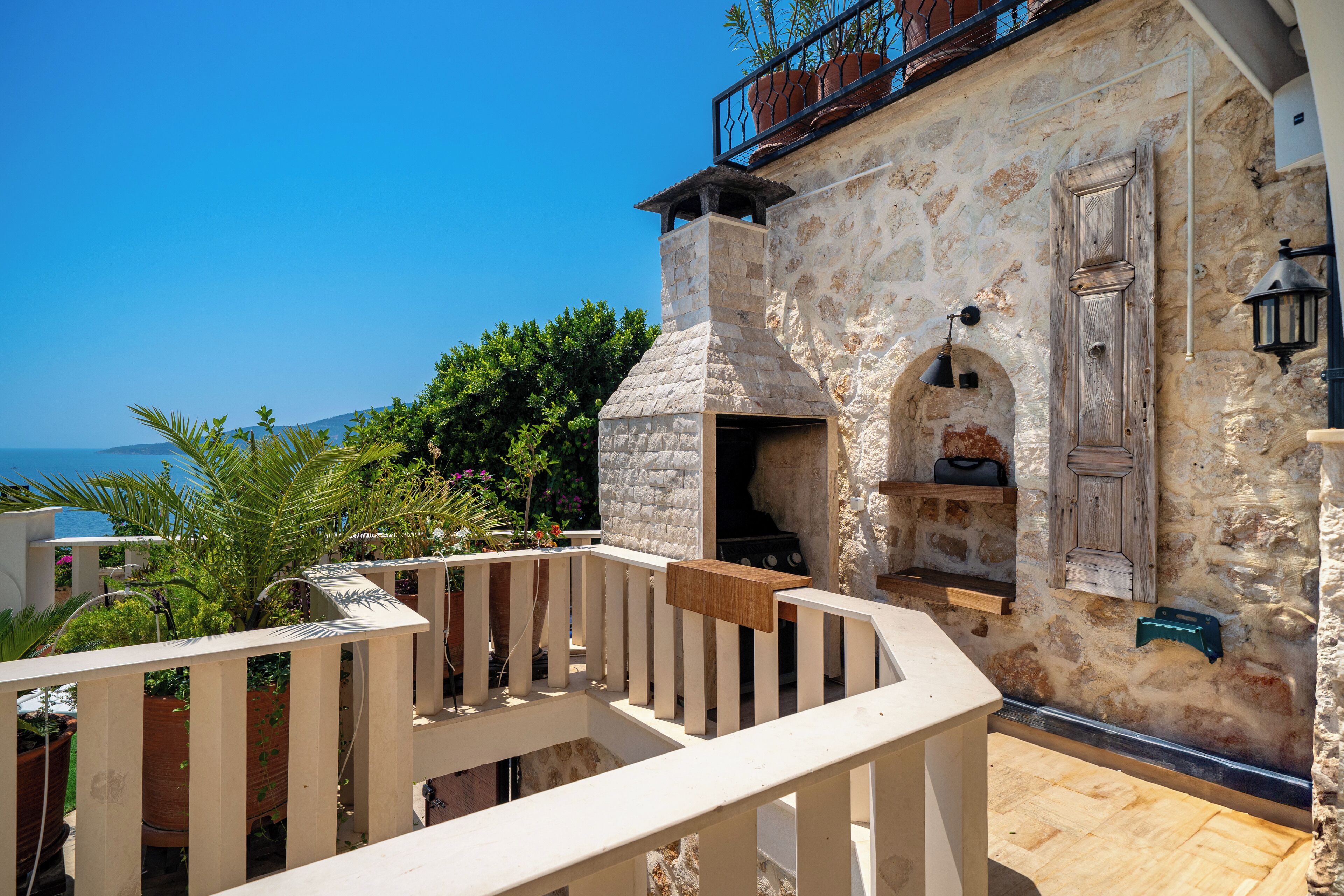Ein Steinhaus mit einem Holzbalkon, einem Schornstein und Blick auf das Meer.