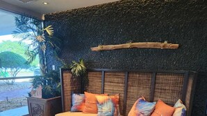 A modern living room with a sofa, colorful cushions, a glass coffee table, and a textured wall. - Harbor Haven Escape (Ruskin)