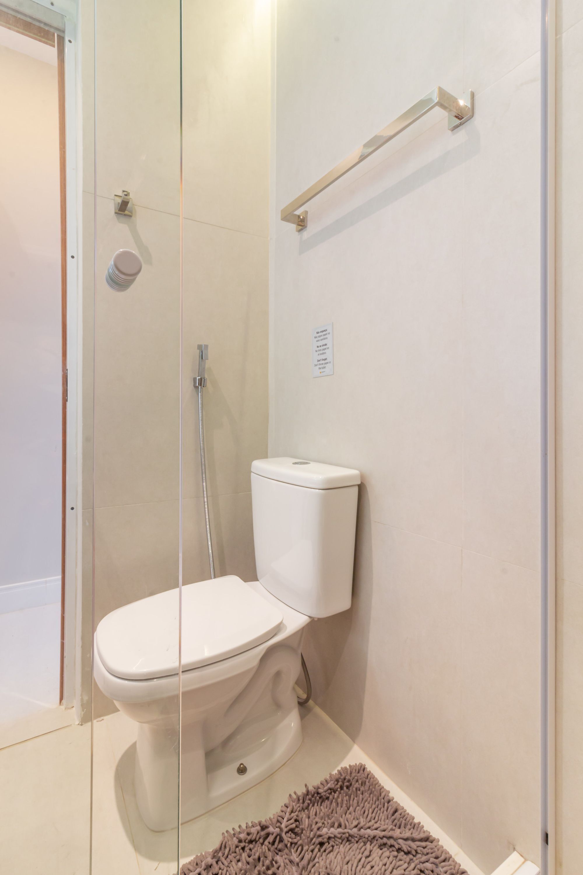 A bathroom with a toilet, a glass shower enclosure, and a towel rack.