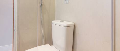 A bathroom with a toilet, a glass shower enclosure, and a towel rack.
