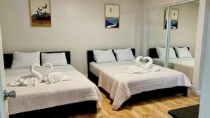Ett hotellrum med två sängar, var och en med ett vitt sängöverkast och kuddar. På väggarna hänger konstverk som föreställer landskap, och det finns en spegel på väggen.