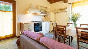A cozy kitchen with a dining area, wooden furniture, and a window with curtains.