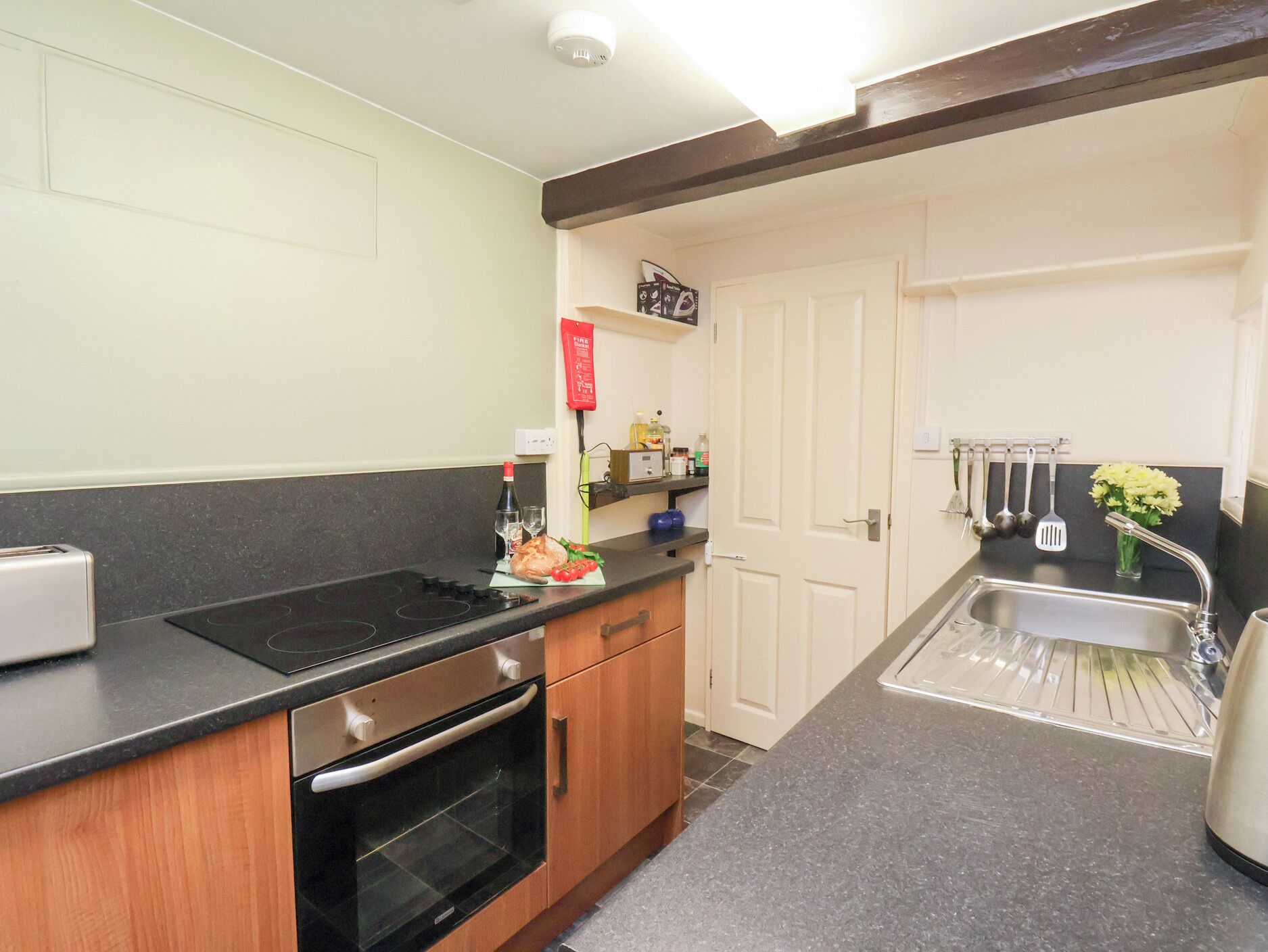 A kitchen with a black countertop, stainless steel sink, and wooden cabinets.