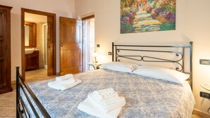 Ein Schlafzimmer mit einem Bett, zwei Nachttischen, einem Gemälde und Holztüren.