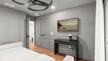 A bedroom with a bed, a desk, a painting, and a door.