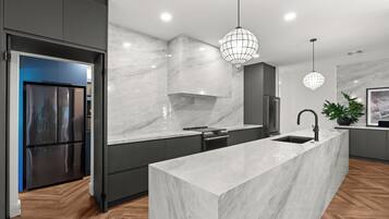 A modern kitchen with a marble countertop, stainless steel appliances, and a central island with a sink.