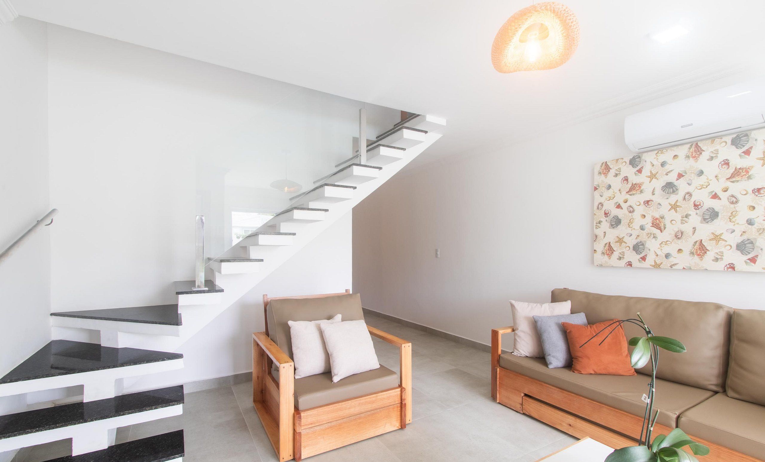 A modern living room with a staircase, a sofa, and a chair.