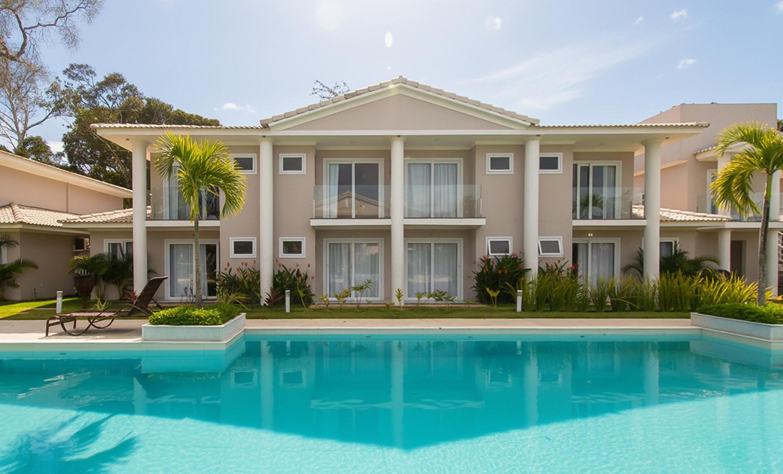 A two-story hotel with a swimming pool in front.