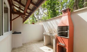 A small outdoor kitchen area with a built-in oven and sink, under a wooden roof structure. - House 2 Suites in Condo w/ Pool Mnt0058 (Porto Seguro)