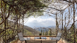 A terrace with a table and chairs, surrounded by a wrought iron fence and climbing plants. - Villa 'Ancòra Tenuta Lonciano' with pool and view (Sesto Fiorentino)