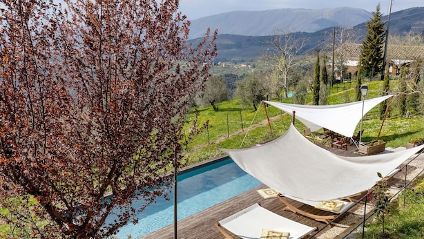 A poolside area with a wooden deck, lounge chairs, and a white canopy. - Villa 'Ancòra Tenuta Lonciano' with pool and view (Sesto Fiorentino)