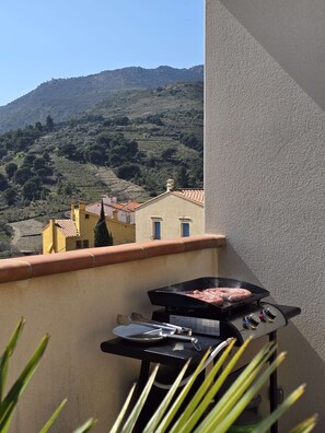 Ein Balkon mit Grill und Blick auf eine hügelige Landschaft.