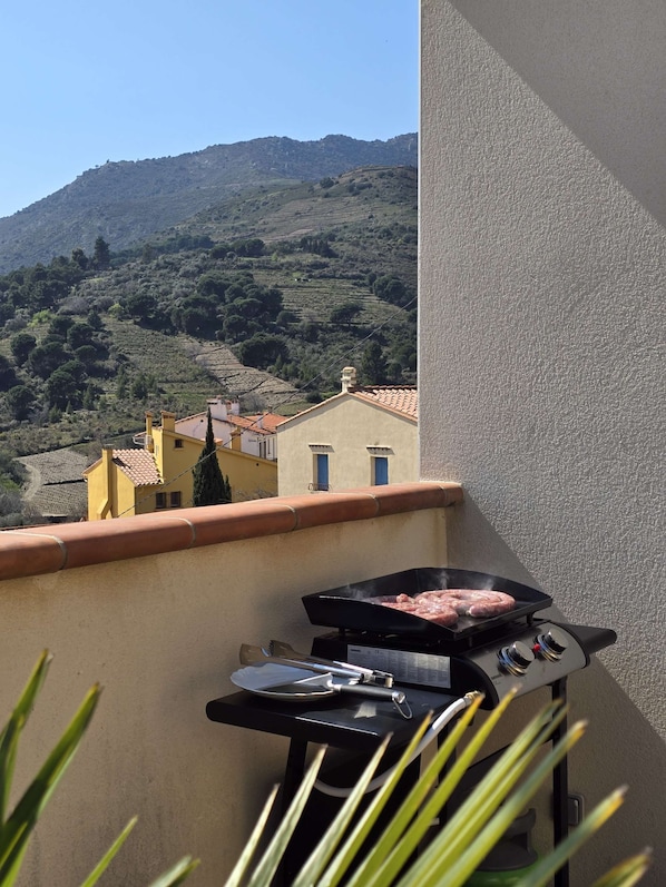 A balcony with a barbecue grill and a view of a hilly landscape. - Le Nid de Paulilles in Port-Vendres (Port-Vendres)
