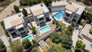 Ein Wohnkomplex mit mehreren Gebäuden, jedes mit einem Schwimmbecken und Außenbereich zum Entspannen.