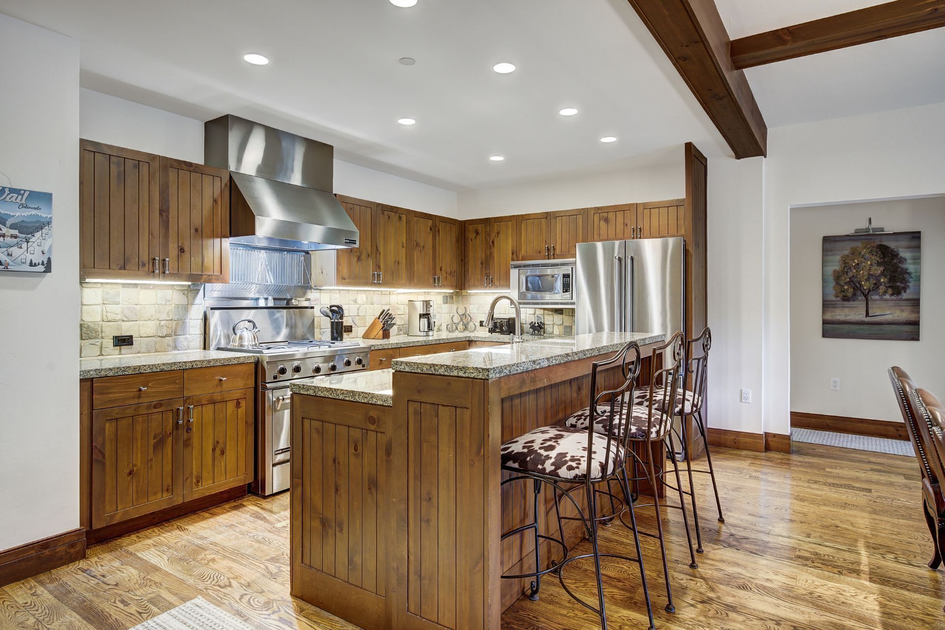 A modern kitchen with wooden cabinets, stainless steel appliances, and a central island with bar stools.
