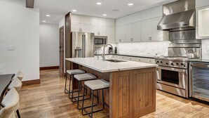 A modern kitchen with stainless steel appliances, a marble countertop, and wooden accents. - Platinum 3BR Beaver Creek Condo | Ski-in/Ski-out (Avon)
