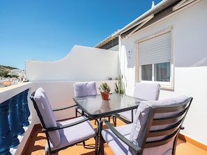 A balcony with a glass table and chairs, a potted plant, and a view of the sea. - Dappan Bleu Apartment, Burgau, Algarve (Burgau)