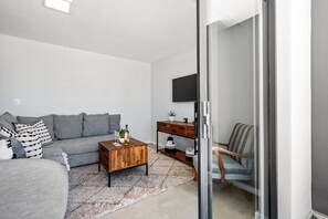 Een woonkamer met een bank, salontafel en een aan de muur bevestigde televisie.