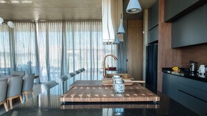 Eine moderne Küche mit Granitarbeitsplatte, einem Essbereich mit Holztisch und -stühlen sowie einem großen Fenster mit leichtem Vorhang.