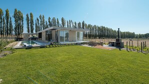 Ein modernes Haus mit einem großen Panoramafenster, einem Pool und einem gepflegten Rasen.