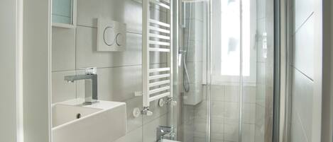 A modern bathroom with a glass shower enclosure, a built-in sink, and a vanity with a mirror.