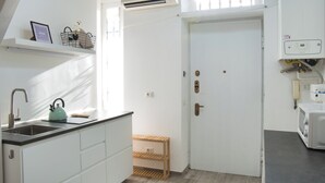 A modern kitchen with a sink, kettle, and a wooden shelf. - Cozy Navigli Loft - One Bedroom Apartment, Sleeps 2 (Milano)