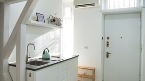 A kitchen with a sink, a kettle, and a small wooden shelf. - Cozy Navigli Loft - One Bedroom Apartment, Sleeps 2 (Milano)