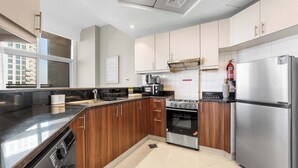 A modern kitchen with wooden cabinets, stainless steel appliances, and a built-in washer. - Stayshort - Stylish 1-bedroom Home Fully Furnished in JVC (Dubai)