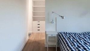 A modern bedroom with a bed, a desk, and a wardrobe.
