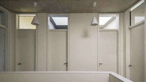 A modern bathroom with white lockers, skylights, and pendant lights.