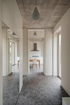 A modern interior with a kitchen area, a dining table, and a large mirror.