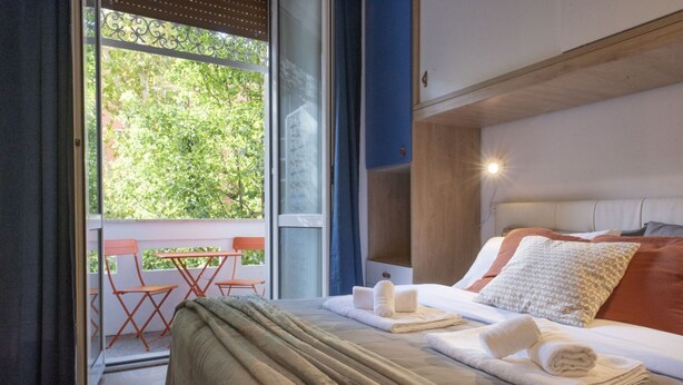 Una habitación de hotel con cama, una mesa y sillas cerca de un ventanal corredero.