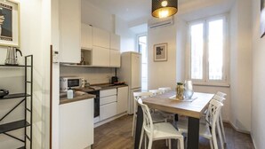 Una cocina moderna con armarios blancos, una mesa de comedor de madera y una lámpara colgante negra.