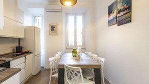Una cocina moderna con armarios blancos, encimera de madera y un comedor con mesa de madera y sillas blancas.
