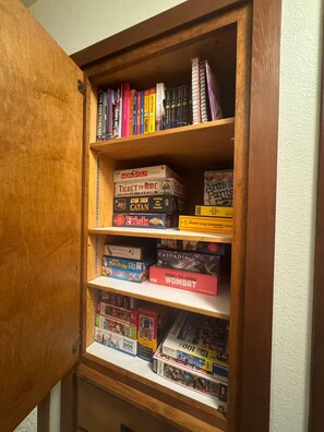 A wooden bookshelf with various board games and books. - Modern Sunriver Retreat – Sleeps 16 (Sunriver)