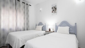 A hotel room with two beds, a nightstand, a lamp, and a wall-mounted light fixture. - Dappan White Apartment, Burgau, Algarve (Burgau)
