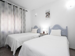 Ein Hotelzimmer mit zwei Betten, einem Nachttisch, einer Lampe und einer Wandleuchte.