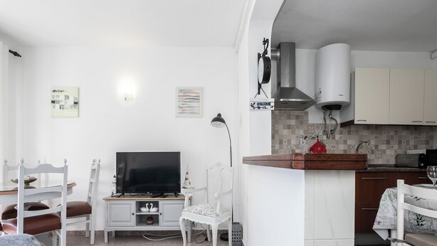 A compact living space with a TV, seating, a kitchen area, and a dining table. - Dappan White Apartment, Burgau, Algarve (Burgau)