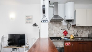 A modern kitchen with a wooden countertop, gas stove, white cabinets, and a TV in the corner. - Dappan White Apartment, Burgau, Algarve (Burgau)