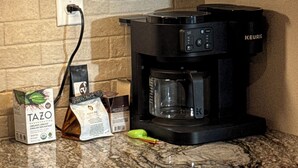 Eine Küche mit einer Kaffeemaschine, einer Packung Tazo-Tee und einer Kaffeetüte auf der Arbeitsfläche.