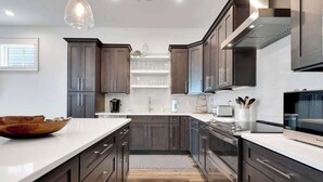 Una cocina moderna con armarios de madera oscura, encimeras blancas y una isla grande.