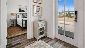 Una habitación con cama, mesita de noche, pequeño armario y ventana grande con vistas al exterior.