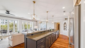 Una cocina moderna con una isla grande, muebles oscuros e iluminación colgante.