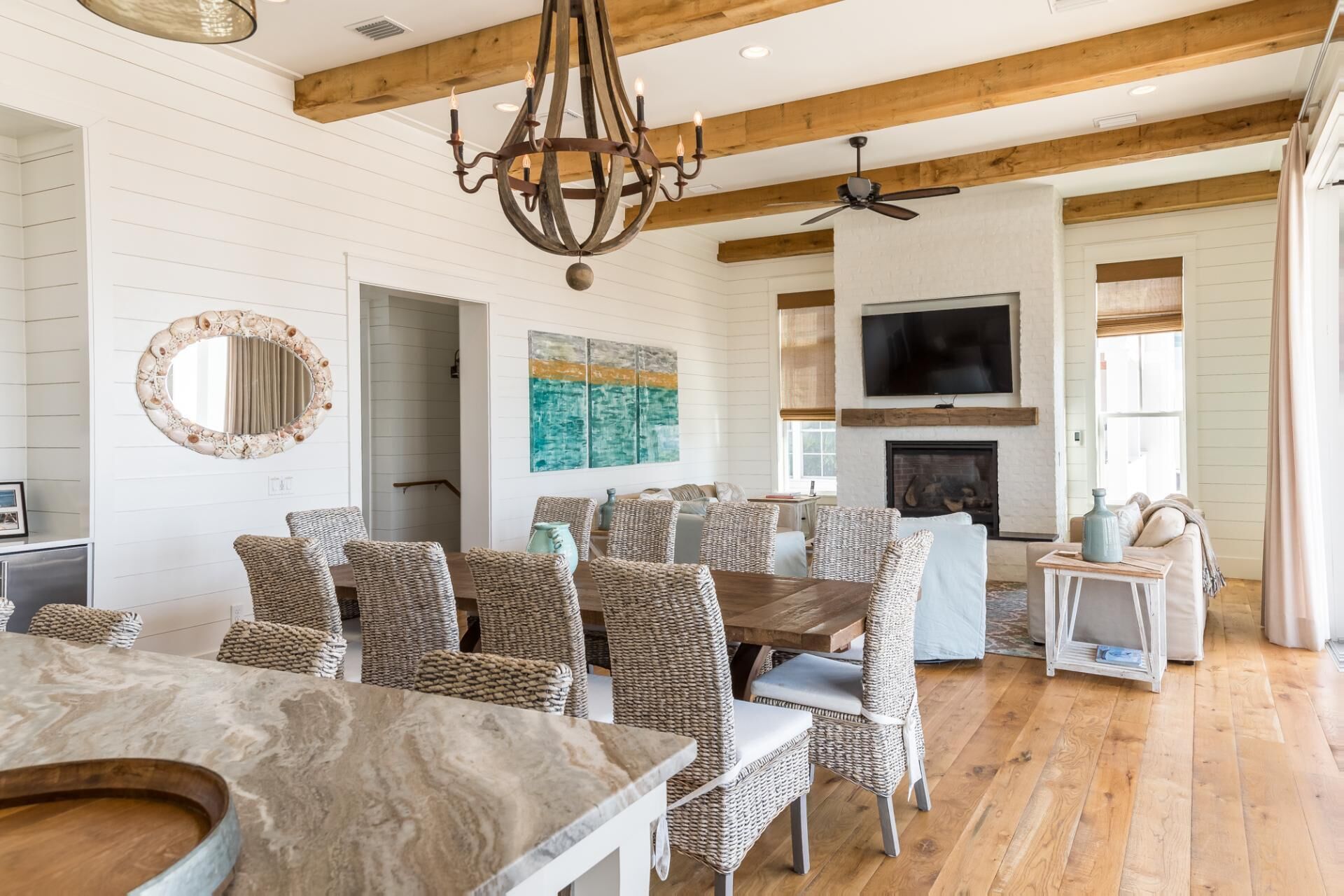 A spacious living room with a fireplace, a large TV, and a dining area with wicker furniture.