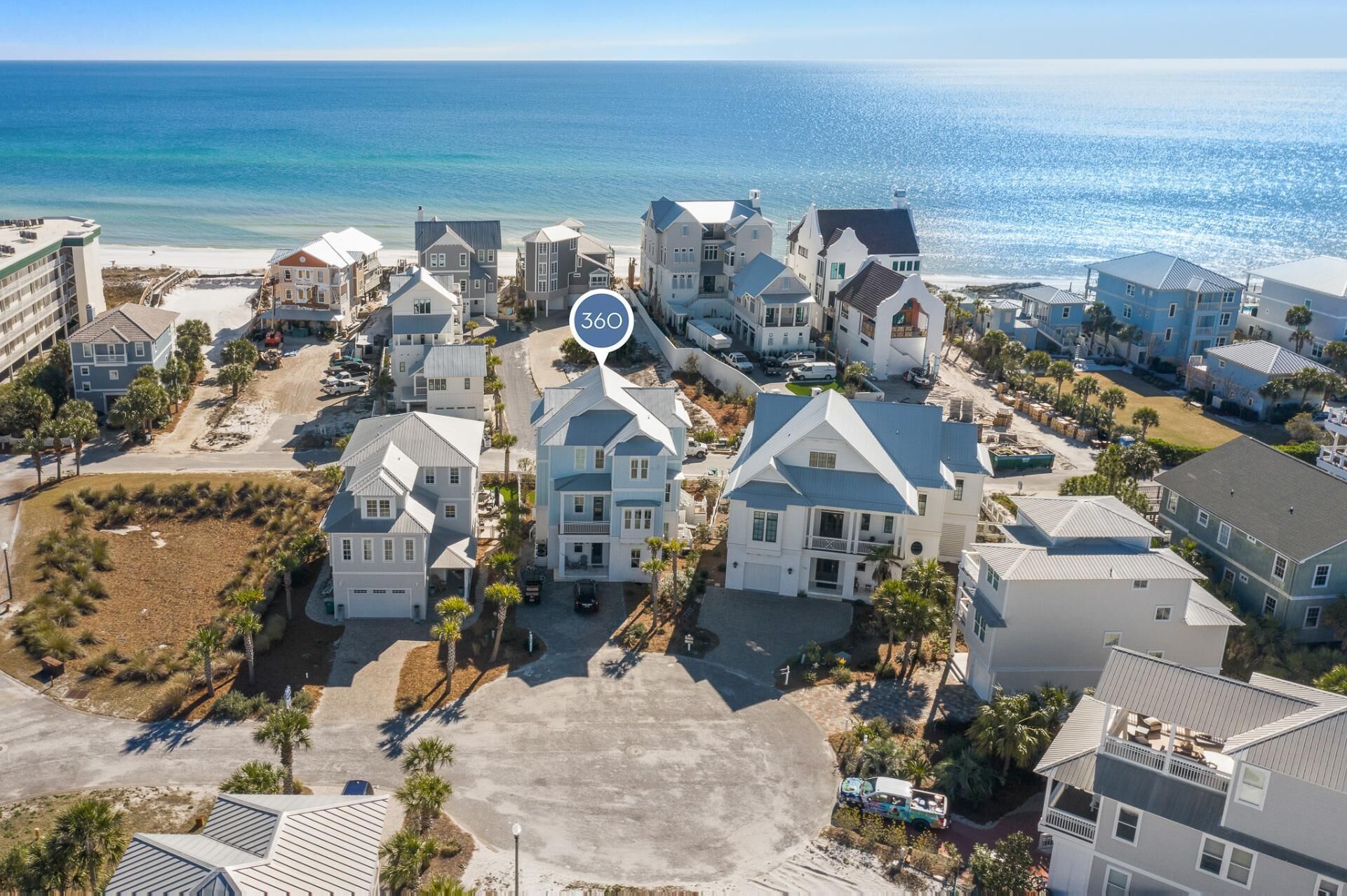 A coastal residential area with multiple two-story houses, a clear view of the ocean, and a large open parking area.
