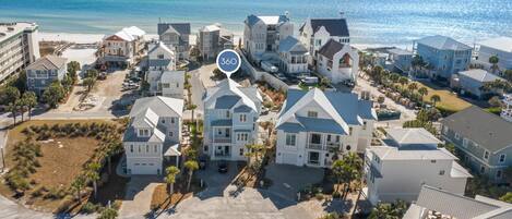 A coastal residential area with multiple two-story houses, a clear view of the ocean, and a large open parking area.